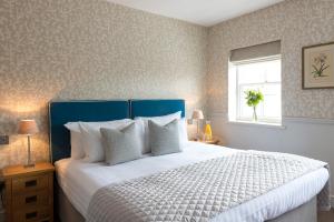 a bedroom with a large bed with a blue headboard at Best Western The Rose & Crown Hotel in Colchester