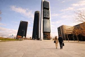 a man and woman walking down a street with tall buildings at Winahost Madrid Towers II in Madrid