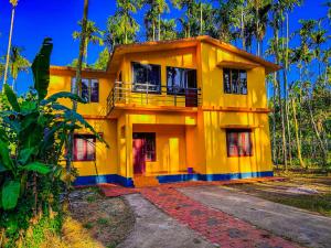 a yellow house in the middle of a forest at Palm Resort in Gūdalūr