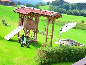 a small playground with a wooden play structure and an umbrella at Bauernhof König in Zwiesel