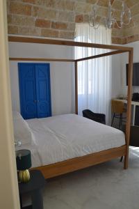 a bedroom with a canopy bed with a blue door at DuOr Suite & Rooms in Polignano a Mare