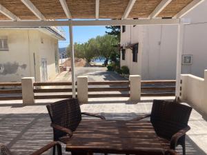 a wooden table and chairs on a porch with stairs at Agioi Apostoloi apartments in Agioi Apostoli