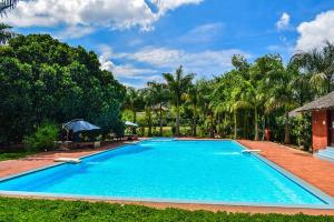 a large blue swimming pool with trees in the background at Red Earth Kabini in Begūr +40 photos