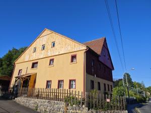 a large brown and yellow building with a fence at Arcoiris in Seifhennersdorf