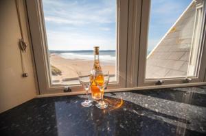 a bottle and two glasses on a table in front of a window at Hartland Heights in Woolacombe