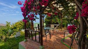 a patio with a table and pink flowers on a tree at The Good Vibes Home in Hoya de Pineda