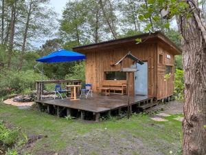 a wooden cabin with a table and an umbrella at La Cabane du Bûcheron in La Teste-de-Buch