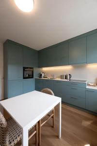a kitchen with blue cabinets and a white table at Stadtloft Suites Zürich- Oerlikon in Zurich +92 photos