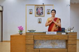 a woman in a sari standing behind a counter at Shyama Inn by Rivlet, Delhi in New Delhi
