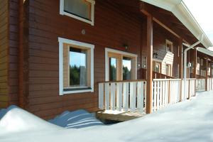 a wooden house with a porch in the snow at Rinnetahko in Tahkovuori