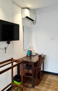 a room with a wooden table and a tv and a table and chairs at Hotel Green Garden PVT LTD in Trincomalee