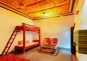 a room with a bunk bed and two chairs at Hotel Goram Garh Resort in Pāli