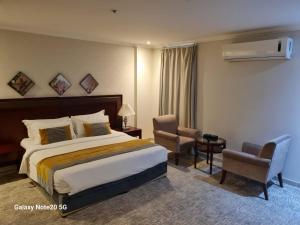 a hotel room with a bed and two chairs at Taleen Serviced Apartments Al-Ahsa- تالين الاحساء للشقق المخدومة in Ruqaiqah