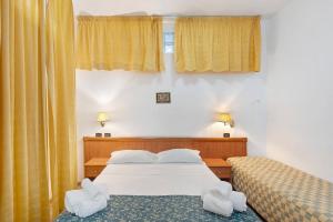 a bedroom with two beds and yellow curtains at B&B H Pompeii Ruins in Pompei
