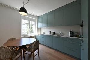 a kitchen with blue cabinets and a table at Stadtloft Suites Zürich- Oerlikon in Zurich