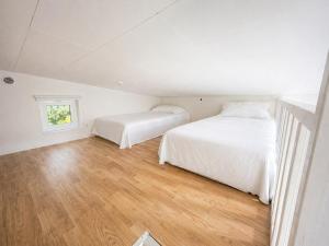 two beds in a white room with wood floors at The Pearl of Södertälje in Södertälje