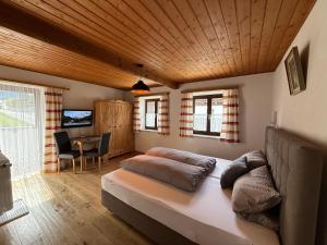 a bedroom with a bed and a table with a television at Gästehaus Zugspitzblick in Berwang