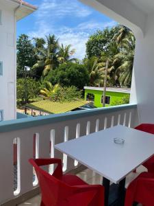 a balcony with a white table and red chairs at La Villa Therese in Anse Royale