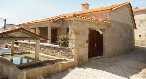 a stone house with a door and a yard at Refugio do Couto in Cabeceiras de Basto