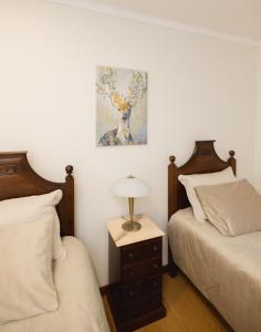 a bedroom with two beds and a lamp on a night stand at Refugio do Couto in Cabeceiras de Basto