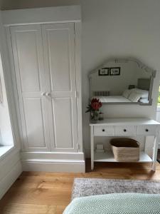 a bedroom with a white cabinet and a mirror at Aeolian House in Cranleigh