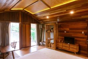 a bedroom with wooden walls and a tv on a table at Saung Komando Ciwidey in Winducina
