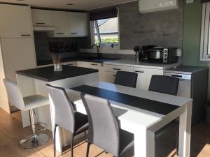 a kitchen with a black and white counter and chairs at Enigma Lounge Chalet with swimming pool in Zutendaal