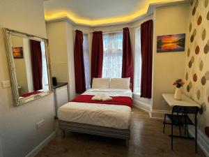a small bedroom with a bed with red curtains at Lyon House Hotel in Barking