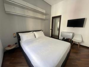 a bedroom with a white bed and a television at ROOMITO apartments in Naples