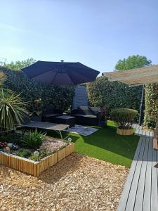a garden with an umbrella and a table and chairs at Joli Appartement Audenge in Audenge