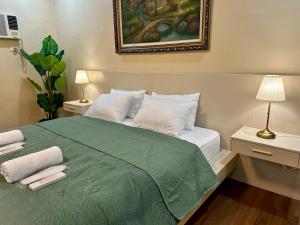 a bedroom with a green bed with two lamps and a painting at The Penthouse at Sapphire in San Agustin +31 photos