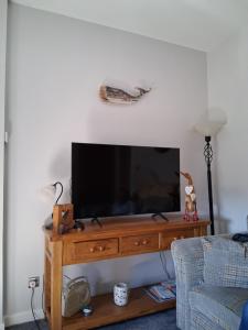 a flat screen tv sitting on top of a wooden entertainment center at DRIFTWOOD coastal holiday flat - newly refurbished with 2 bedrooms in Largs
