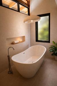 a large white tub in a bathroom with a window at Vista Naranja Retreat in Santa Teresa Beach
