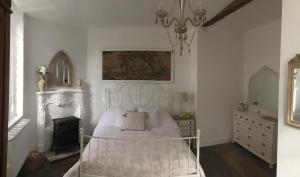 1 dormitorio con cama blanca y lámpara de araña en La Maison Du Pont, en La Rochebeaucourt-et-Argentine