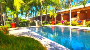 a swimming pool in front of a building with palm trees at Fleurs d'Ylang in Nosy Be