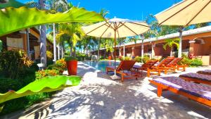 a patio with chairs and umbrellas next to a pool at Fleurs d'Ylang in Nosy Be
