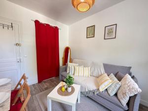 a living room with a couch and a red door at Studio cosy parking in Margny-lès-Compiègne