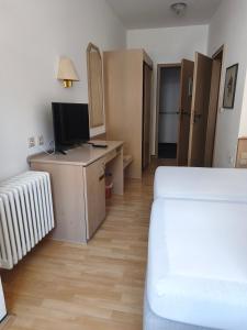 a room with a bed and a desk with a television at Vinami Hotel - Bad Wildbad in Bad Wildbad