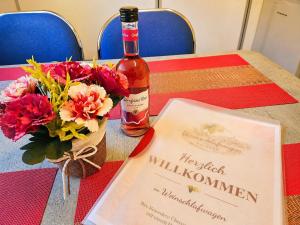 a bottle of wine and a book on a table with flowers at Weinschlafwagen Bautzen in Bautzen