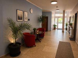 a waiting room with a table and chairs and a clock at Pension Lara in Magdeburg