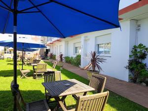 a wooden table and chairs with a blue umbrella at Hotel Rodeiramar in Cangas de Morrazo