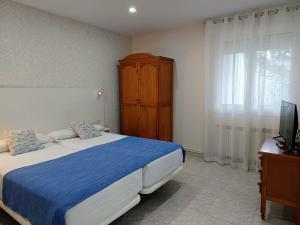 a bedroom with a bed and a dresser and a television at Hotel Rodeiramar in Cangas de Morrazo
