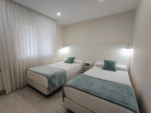 a hotel room with two beds and a window at Hotel Rodeiramar in Cangas de Morrazo