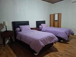 two beds in a room with purple blankets at Rumah Pantai Patang in Jati
