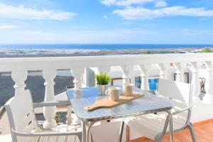 a table on a balcony with a view of the ocean at Finca La Calera Lanzarote - Calma in Güime