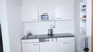 a white kitchen with a sink and a microwave at Appelholt in Wremen