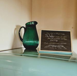 a green vase sitting on a shelf next to a sign at The Forgotten Farmhouse in Skogar