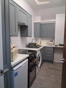 a kitchen with white cabinets and a stove top oven at DRIFTWOOD coastal holiday flat - newly refurbished with 2 bedrooms in Largs