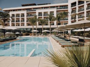 a hotel with a swimming pool with chairs and umbrellas at Aguas de Ibiza by NCalma Hotels in Santa Eularia des Riu