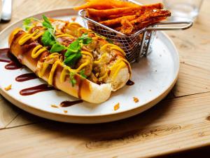 a plate with a hot dog and a basket of fries at ibis Styles Avignon Sud in Avignon